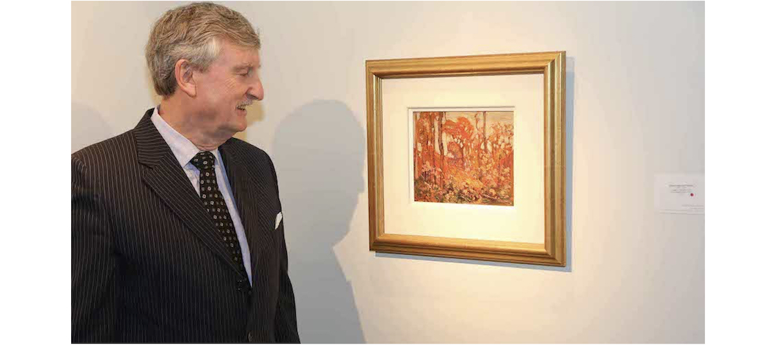 David Loch standing next to Tom Thomson oil painting of autumn trees